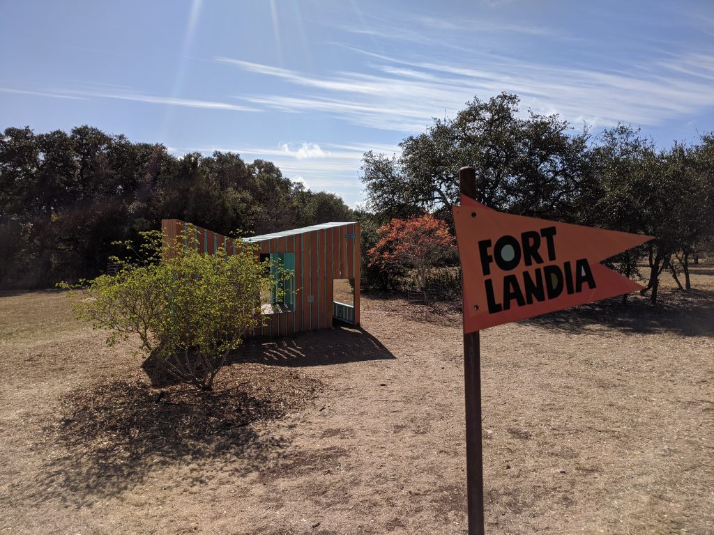 A Fortlandia sign in front of an unusual looking fort.