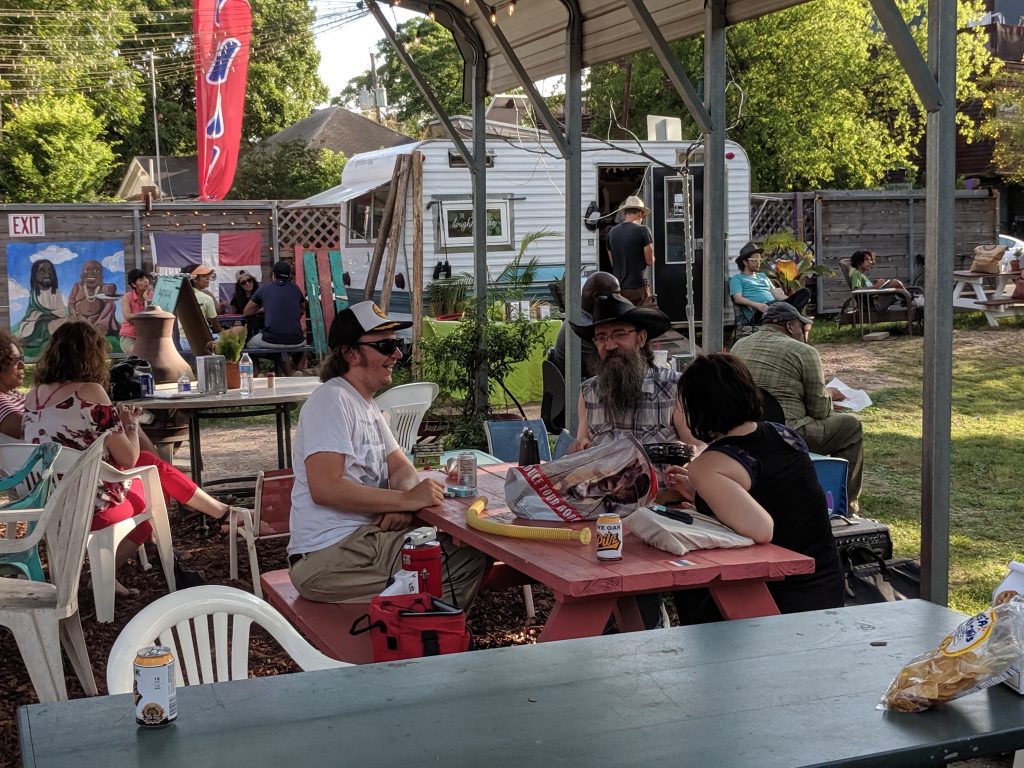 People sitting on a table in the shade at Kenny Dorham's backyard.