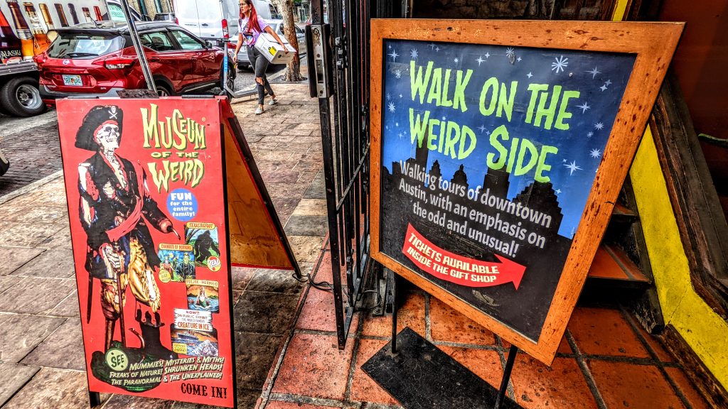 Entrance to the Museum of Weird in Austin featuring two standees advertising the museum. 